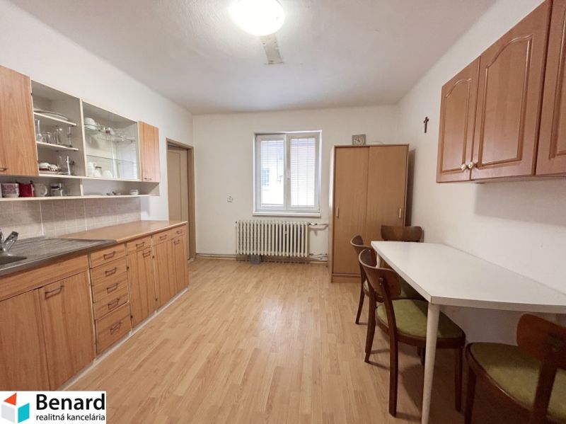 Eine Küche in einem Einfamilienhaus mit einem Boden in Holzoptik, Holzschränken und einem Esstisch.