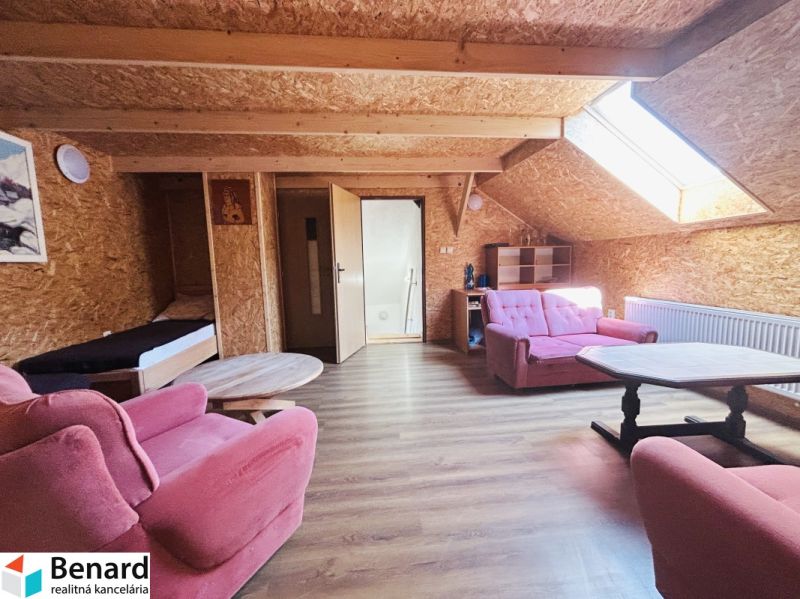 Ein Dachzimmer in einem Einfamilienhaus mit rosa Möbeln und einem Boden in Holzoptik.