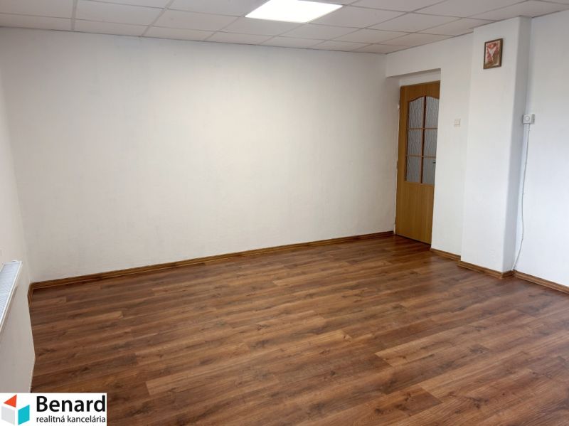 Ein Zimmer in einem Einfamilienhaus mit weißen Wänden und einem Boden in Holzoptik.