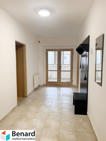 Flur mit Garderobe und Fliesen in einem Einfamilienhaus, die Tür führt auf die verglaste Terrasse.