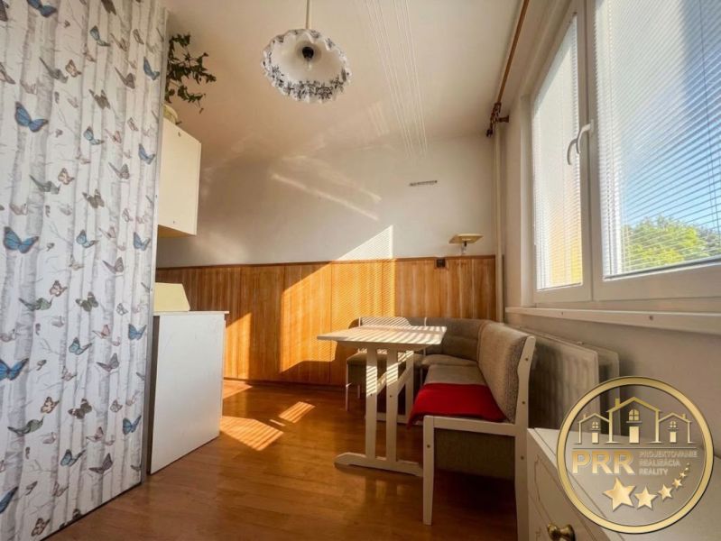 Essecke in einer Zweizimmerwohnung mit Holzboden und Tapete mit Schmetterlingsmuster.