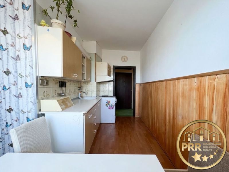 Küche in einer 2-Zimmer-Wohnung mit Holzboden-Dekor und weißen Schränken.