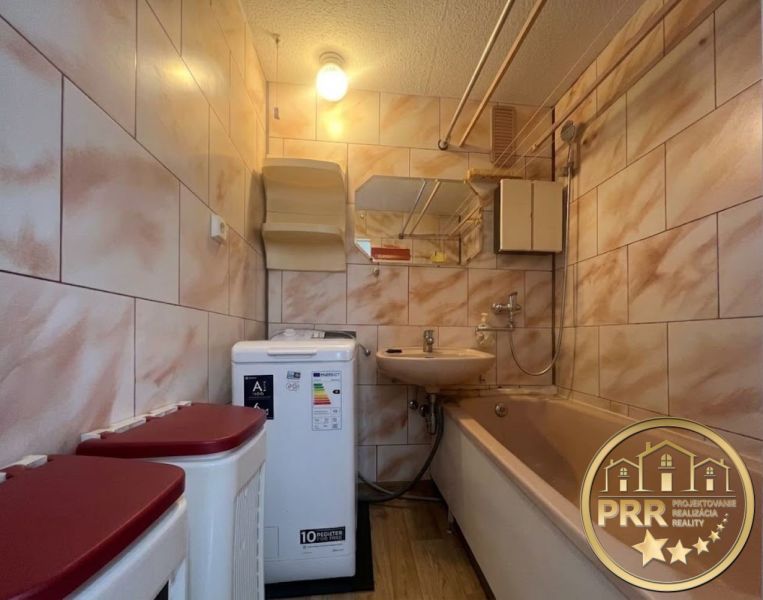Badezimmer in einer 2-Zimmer-Wohnung mit Badewanne, Waschbecken, Waschmaschine und Fliesen.