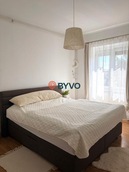Schlafzimmer in einer 2-Zimmer-Wohnung mit einem bequemen Bett und einem Boden in Holzoptik.