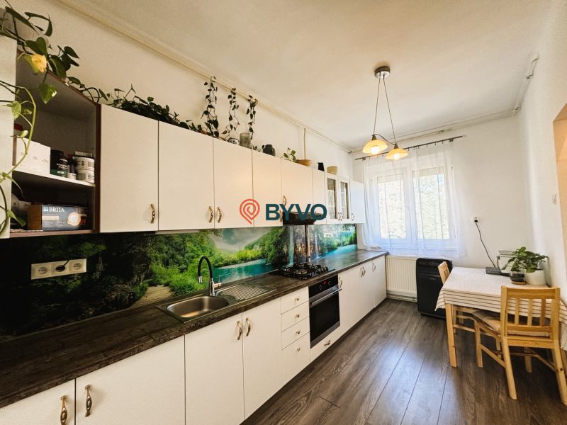 Küche mit Küchenzeile, Tisch und Boden mit Holzdekor in einer 2-Zimmer-Wohnung.