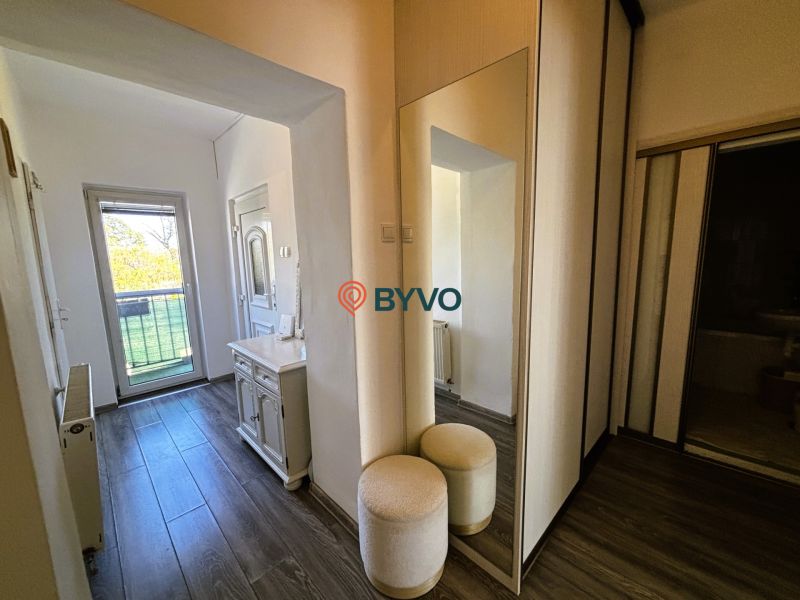 Der Flur in einer 2-Zimmer-Wohnung mit einem Spiegel und einem Boden in Holzoptik.