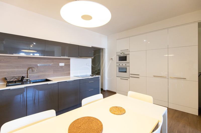 Küche in einer Einzimmerwohnung mit eleganten Schränken und einem hellen Esstisch.