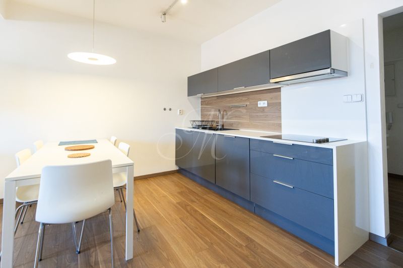 Küche einer Einzimmerwohnung mit Esstisch und Boden in Holzoptik.