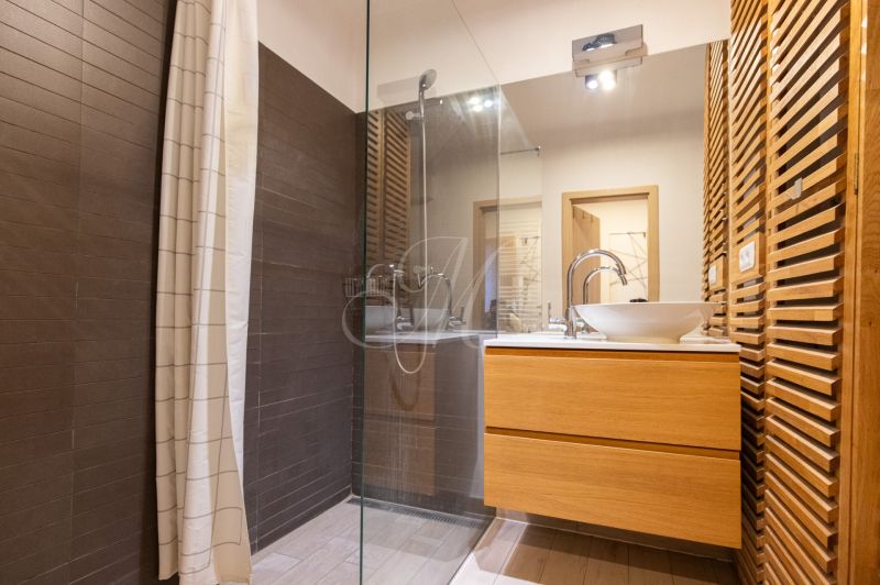 Ein Badezimmer in einer Einzimmerwohnung mit Holzelementen und einer Duschkabine.