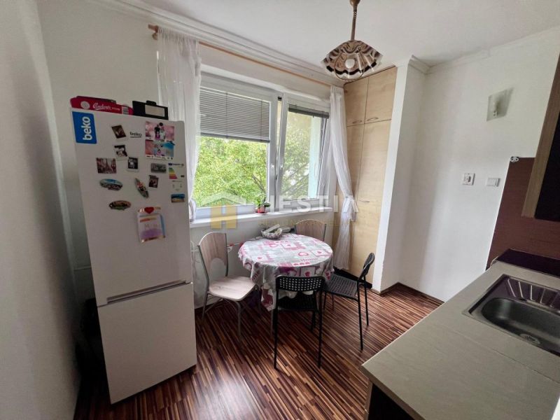 Küche in einer 2-Zimmer-Wohnung mit Holzboden, Esstisch und Kühlschrank.