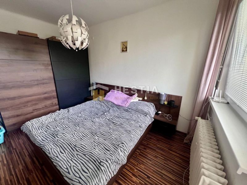 Schlafzimmer in einer 2-Zimmer-Wohnung mit Holzboden, Bett und Schrank.