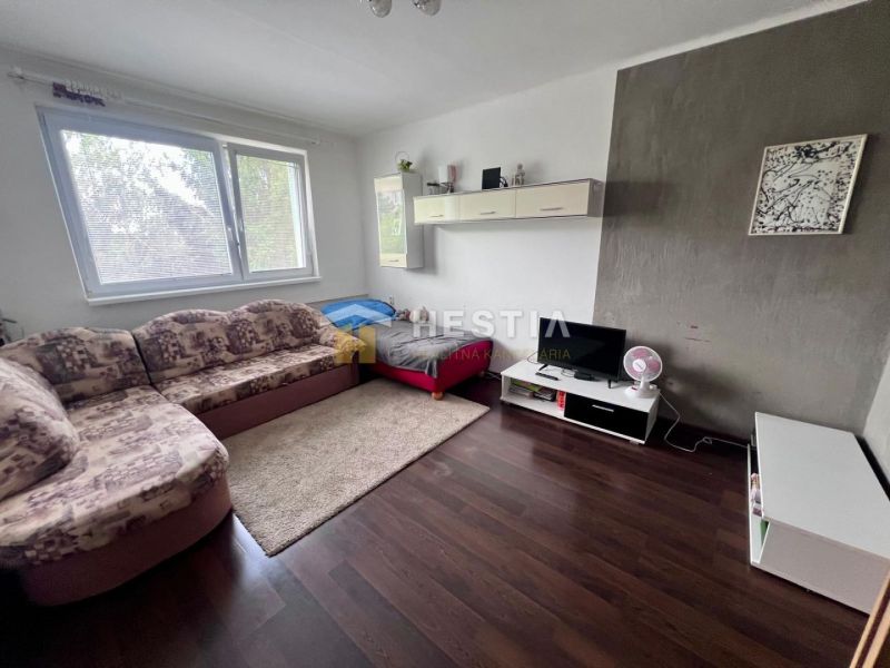 Wohnzimmer mit Ecksofa, TV-Schrank und Holzboden in einer 2-Zimmer-Wohnung.