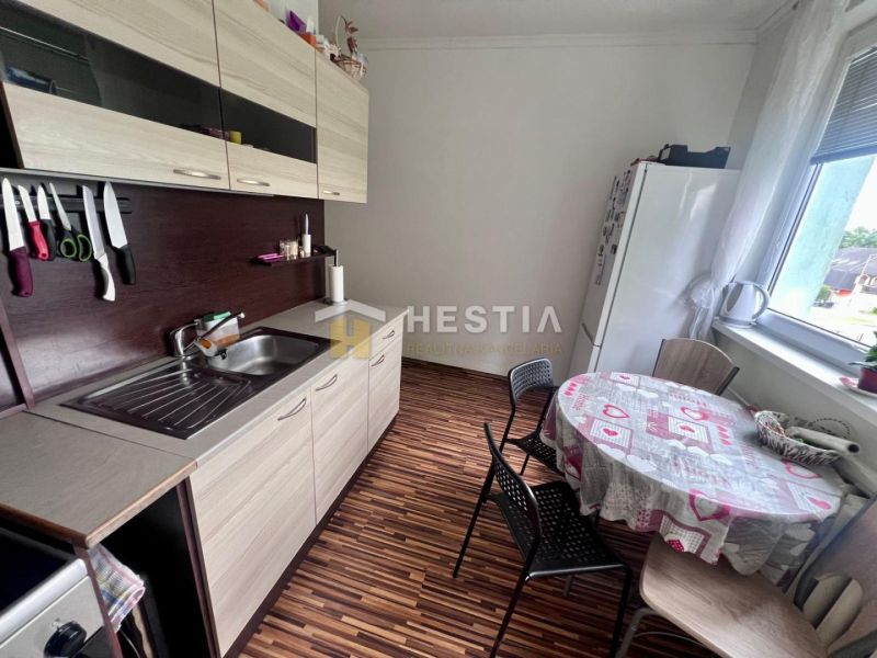 Küche in einer 2-Zimmer-Wohnung mit Holzboden und Vorhängen am Fenster.
