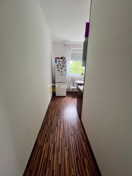 Ein schmaler Flur mit Holzboden führt in die Küche einer Zweizimmerwohnung.