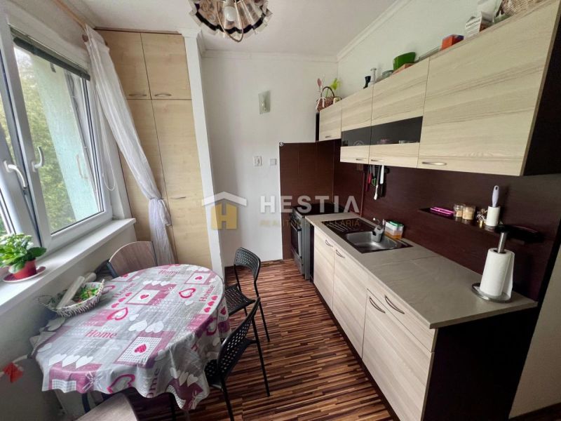 Küche in einer 2-Zimmer-Wohnung mit Holzboden und Esstisch.