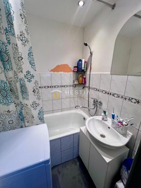 Badezimmer in einer 2-Zimmer-Wohnung mit Dusche, Waschbecken und Waschmaschine.