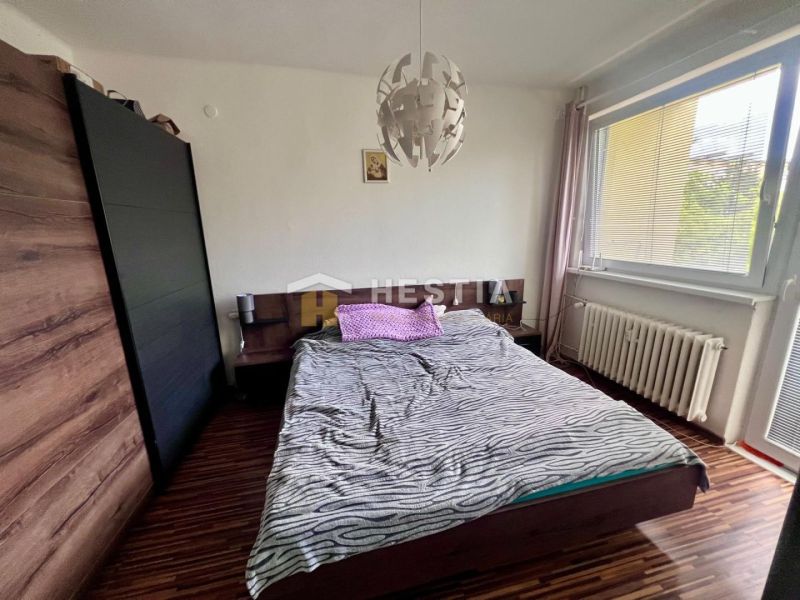 Schlafzimmer in einer 2-Zimmer-Wohnung mit Holzboden und großem Fenster.