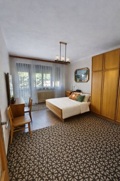 Ein Schlafzimmer in einem Einfamilienhaus mit Teppichboden, einem Bett und Holzmöbeln.