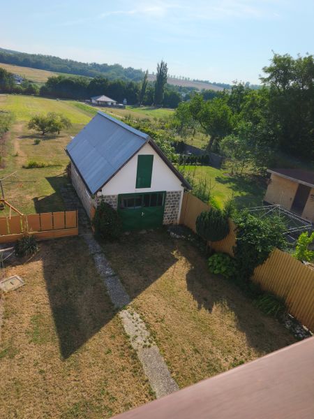 Garten und Gebäude bei einem Einfamilienhaus in Jelenci, umgeben von Feldern und Bäumen.