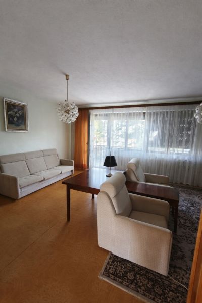 Wohnzimmer in einem Einfamilienhaus mit bequemen Sitzgelegenheiten und großem Fenster.