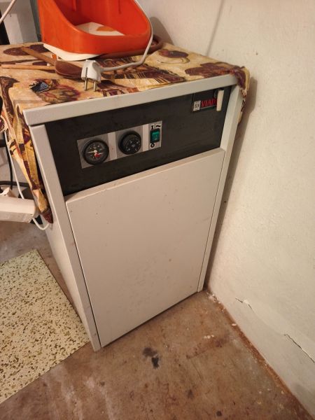 Kessel im Inneren eines Einfamilienhauses mit Bedienfeld und orangefarbenem Behälter oben drauf.