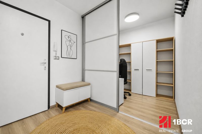 Eingangsbereich mit weißem Schrank, Bank, Dekoration und Boden mit Holzdekor in einer 2-Zimmer-Wohnung.