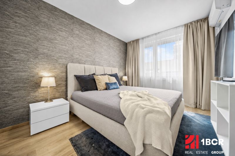 Schlafzimmer mit Bett und Nachttisch, Boden mit Holzdekor in einer 2-Zimmer-Wohnung.