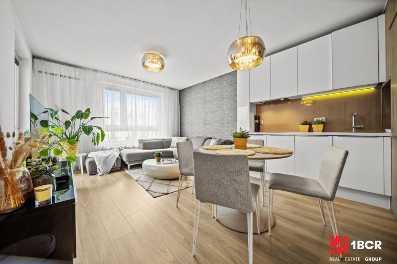 Wohnzimmer in einer 2-Zimmer-Wohnung mit Holzboden, hellen Möbeln und Pflanzen.