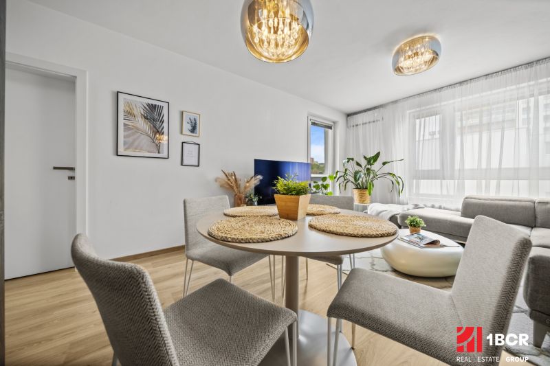 Innenraum einer 2-Zimmer-Wohnung mit Essbereich, Holzboden und elegantem Kronleuchter.