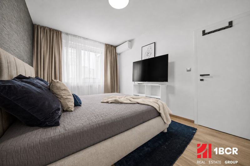 Schlafzimmer mit Bett, Fernseher und Holzboden in einer 2-Zimmer-Wohnung.