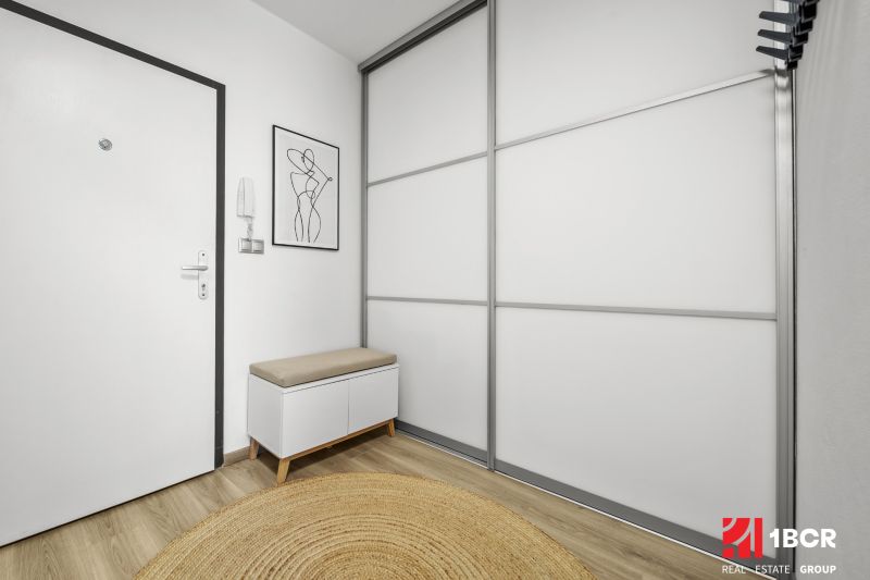 Eingangsbereich in einer 2-Zimmer-Wohnung mit Holzboden und minimalistischen Möbeln.