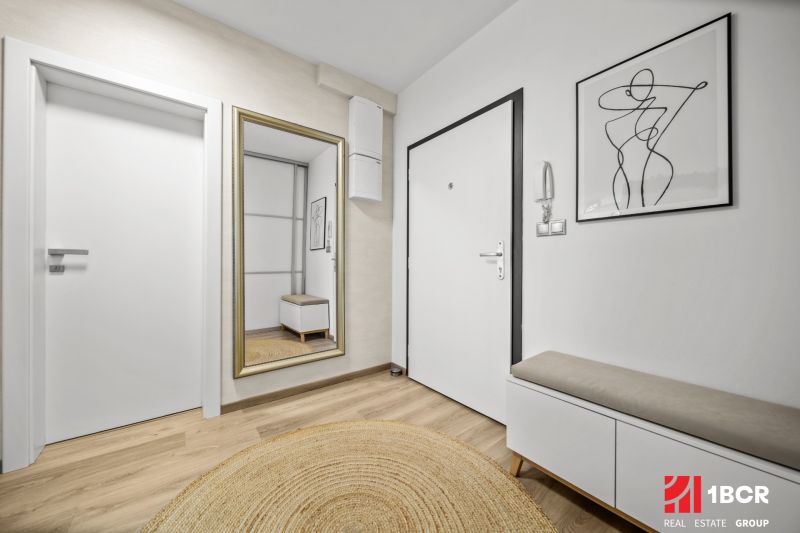 Eingangsbereich in einer 2-Zimmer-Wohnung mit Holzboden und Spiegel.