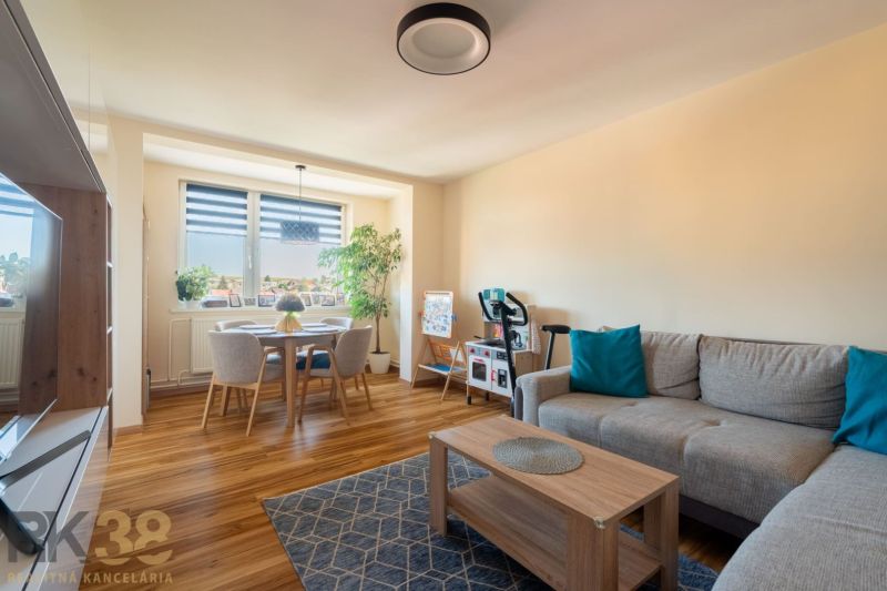 Wohnzimmer mit Sofa und Esstisch, Boden mit Holzdekor.