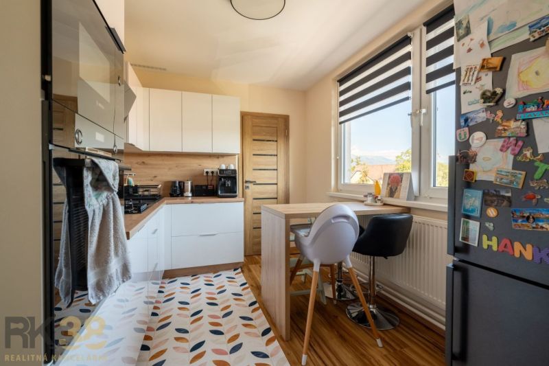 Küche in einer 3-Zimmer-Wohnung mit Holzdekor, weißen Möbeln und dekorativem Teppich.