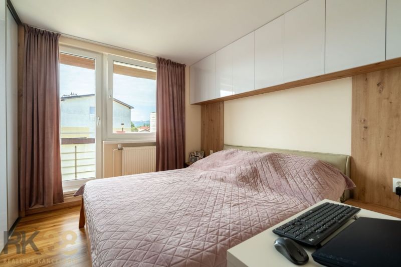 Schlafzimmer mit rosa Überdecke in einer 3-Zimmer-Wohnung, ausgestattet mit einem Boden in Holzoptik.
