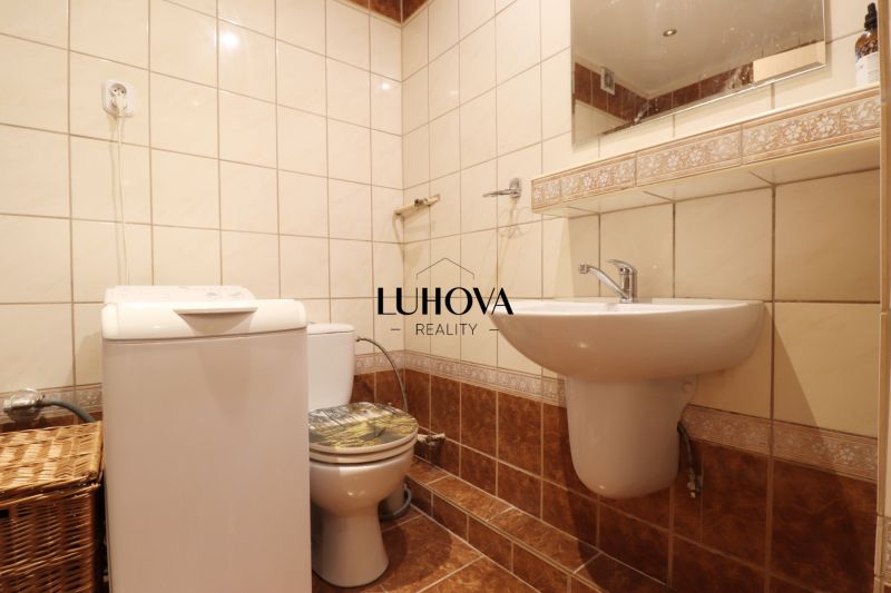 Badezimmer in einer 2-Zimmer-Wohnung mit Waschmaschine und Toilette, Fliesen mit feinem Muster.