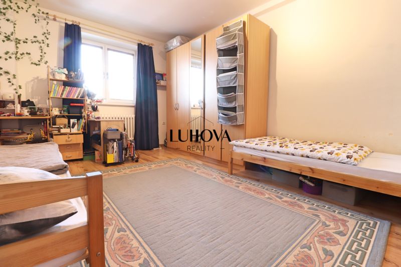 Schlafzimmer mit großem Bett, Schrank, Teppich und Holzboden in einer 2-Zimmer-Wohnung.
