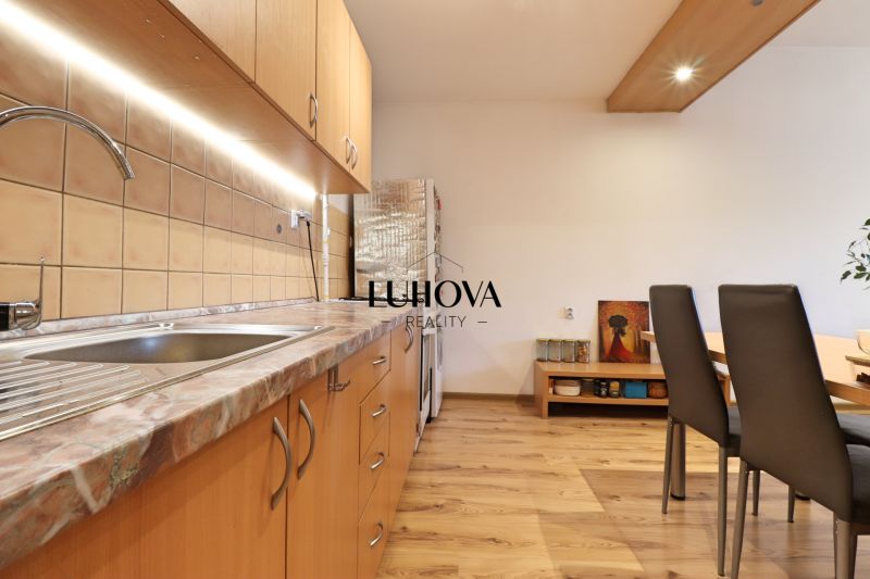 Küche in einer 2-Zimmer-Wohnung mit Holzboden und Holzschränken.