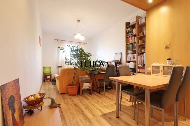 Wohnzimmer mit Holzdekorboden, Sofa, Tisch und Bücherregal in einer Zweizimmerwohnung.