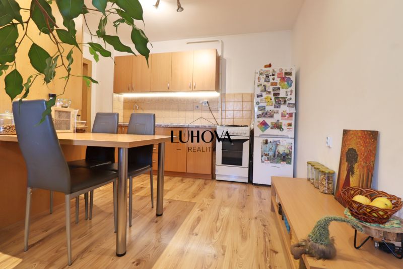 Küche in einer 2-Zimmer-Wohnung mit Holzboden, Esstisch und Kühlschrank.