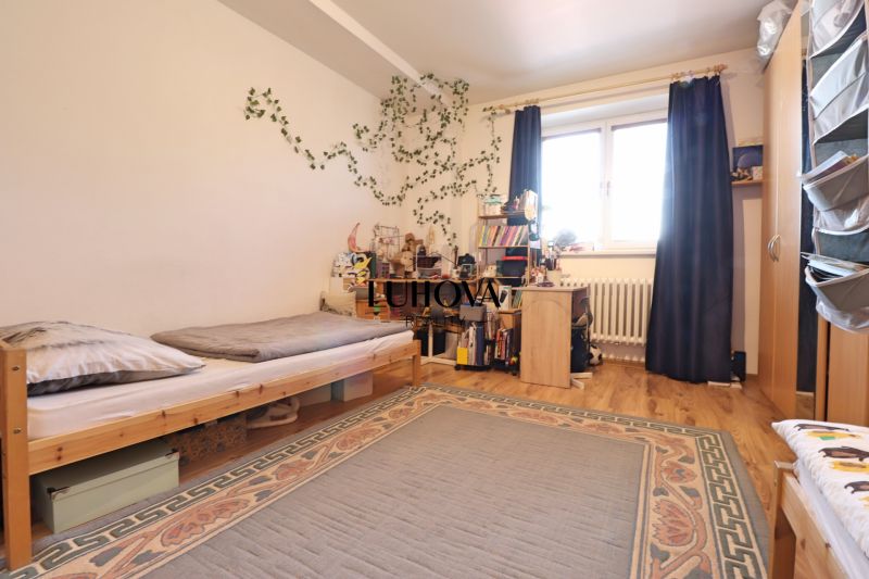 Kinderzimmer in einer Zweizimmerwohnung mit Bett, Tisch und Holzboden-Dekor.