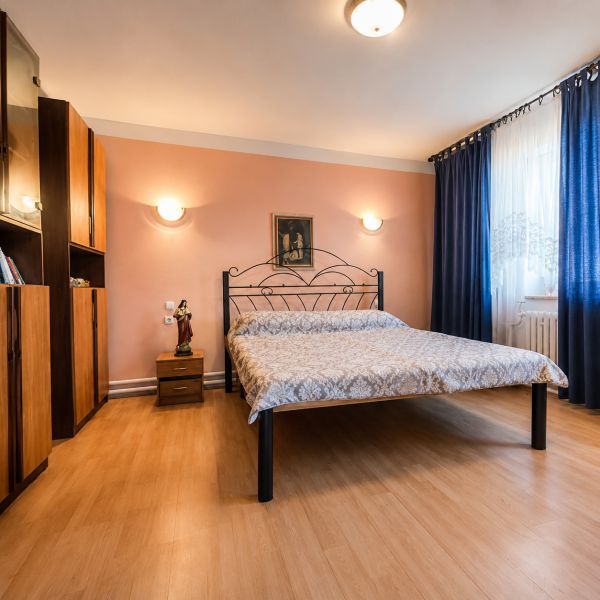 Schlafzimmer mit einem Metallbett, Holzboden, Möbel und Vorhänge in einem Einfamilienhaus.