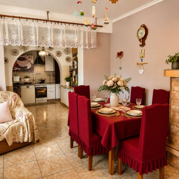 Esszimmer in einem Einfamilienhaus mit roter Tischdecke, Küche und Dekoration mit einer antiken Wanduhr.