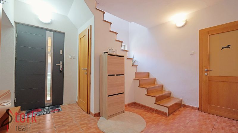 Eingangsflur mit Holzdekor, Treppe und Stauraum in einem Einfamilienhaus.