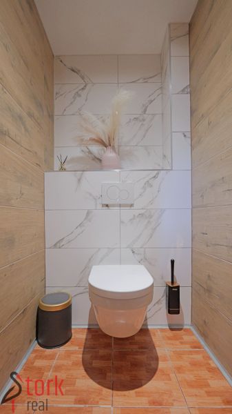 Badezimmer in einem Einfamilienhaus mit Marmoroptik-Fliesen und einem Boden in Holzdekor.