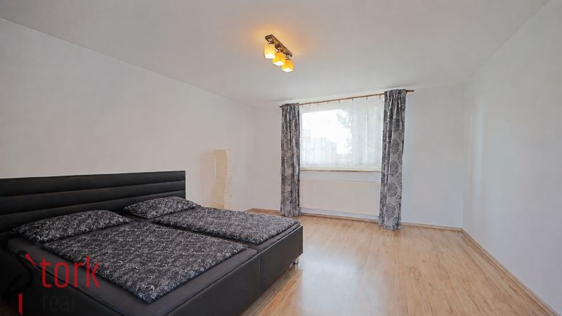 Schlafzimmer in einem Einfamilienhaus mit Bett und Boden in Holzoptik.