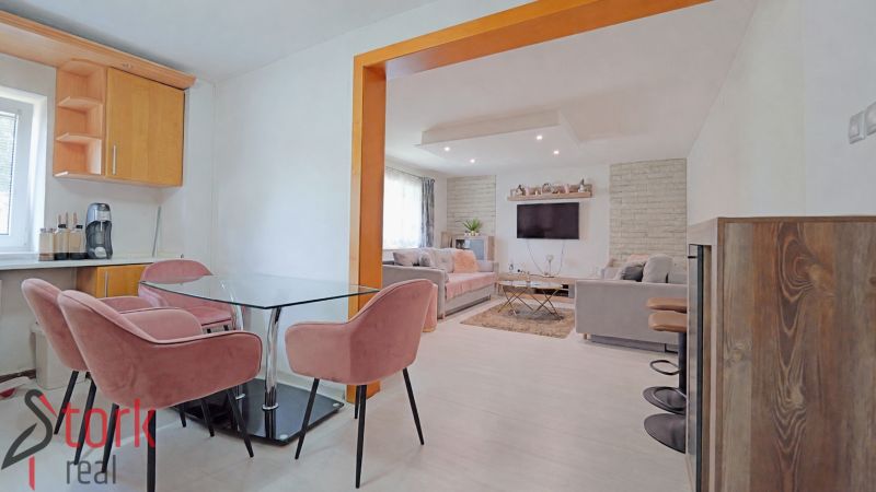 Innenraum eines Einfamilienhauses mit rosa Stühlen, Glastisch und Wohnzimmer mit Sofa.