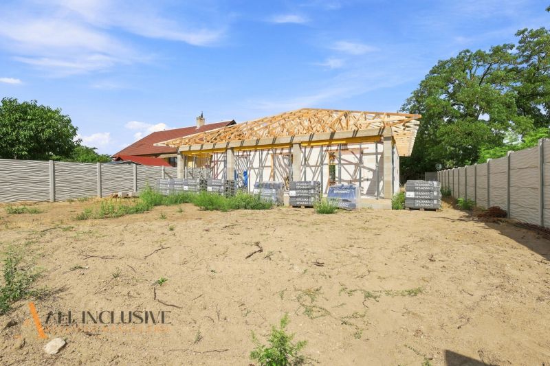 Ein im Bau befindliches Einfamilienhaus in Marcelová mit Umzäunung, stehend auf einem leeren Grundstück mit Rasen.