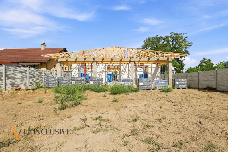 Der Bau eines Einfamilienhauses in Marcelová mit einem im Bau befindlichen Dach und einer Umzäunung.