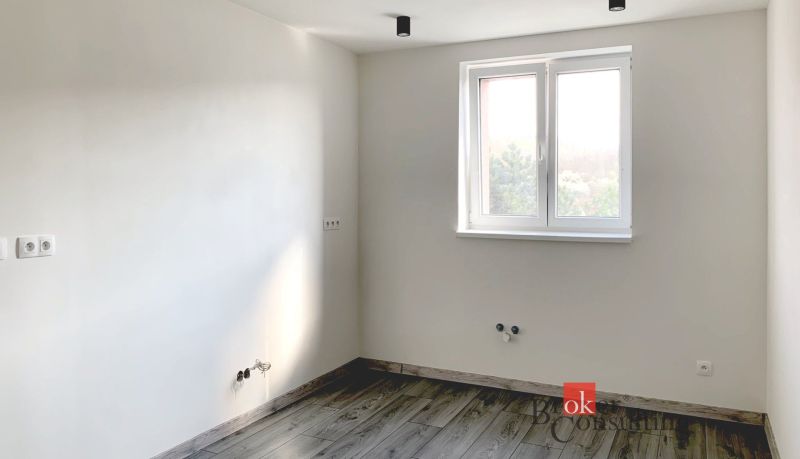 Einfaches Zimmer in einer Einzimmerwohnung mit Holzboden und weißen Wänden.